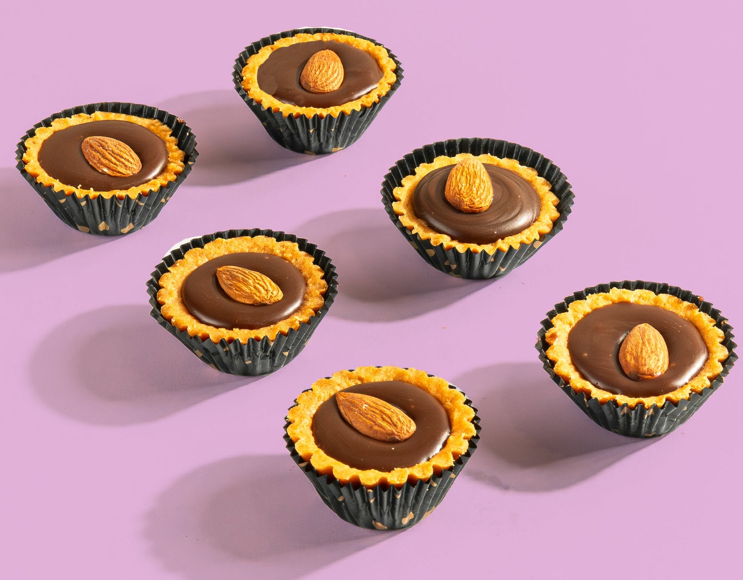Chocolate tarts mini with almonds on a pink background