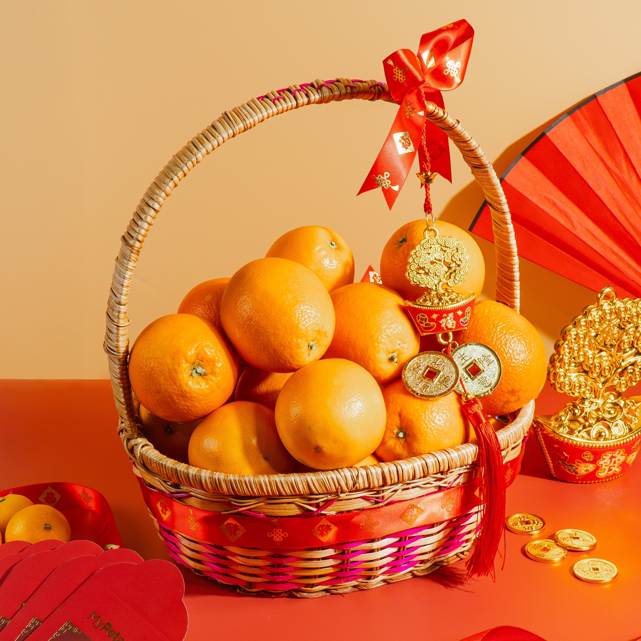 Basket of oranges with red ribbons on a red tablecloth, featuring traditional Chinese elements.