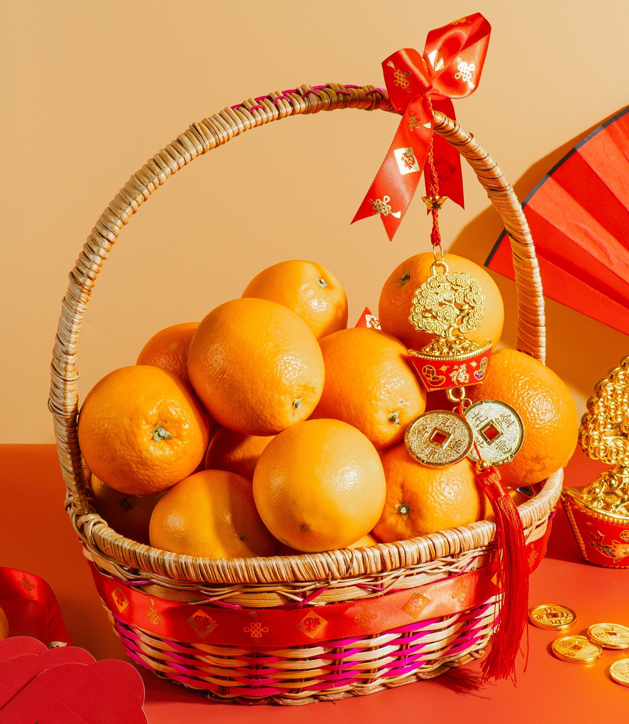 Basket of oranges with red ribbons on a red tablecloth, featuring traditional Chinese elements.