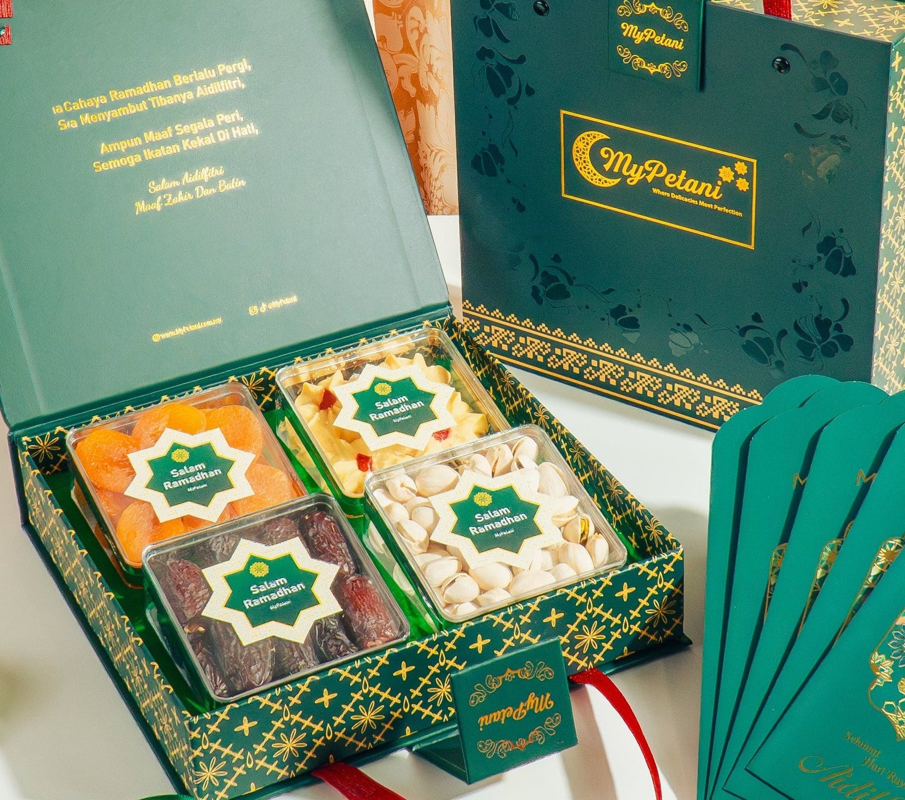 Gift set with green boxes, cookies, and cards on a decorative tablecloth.