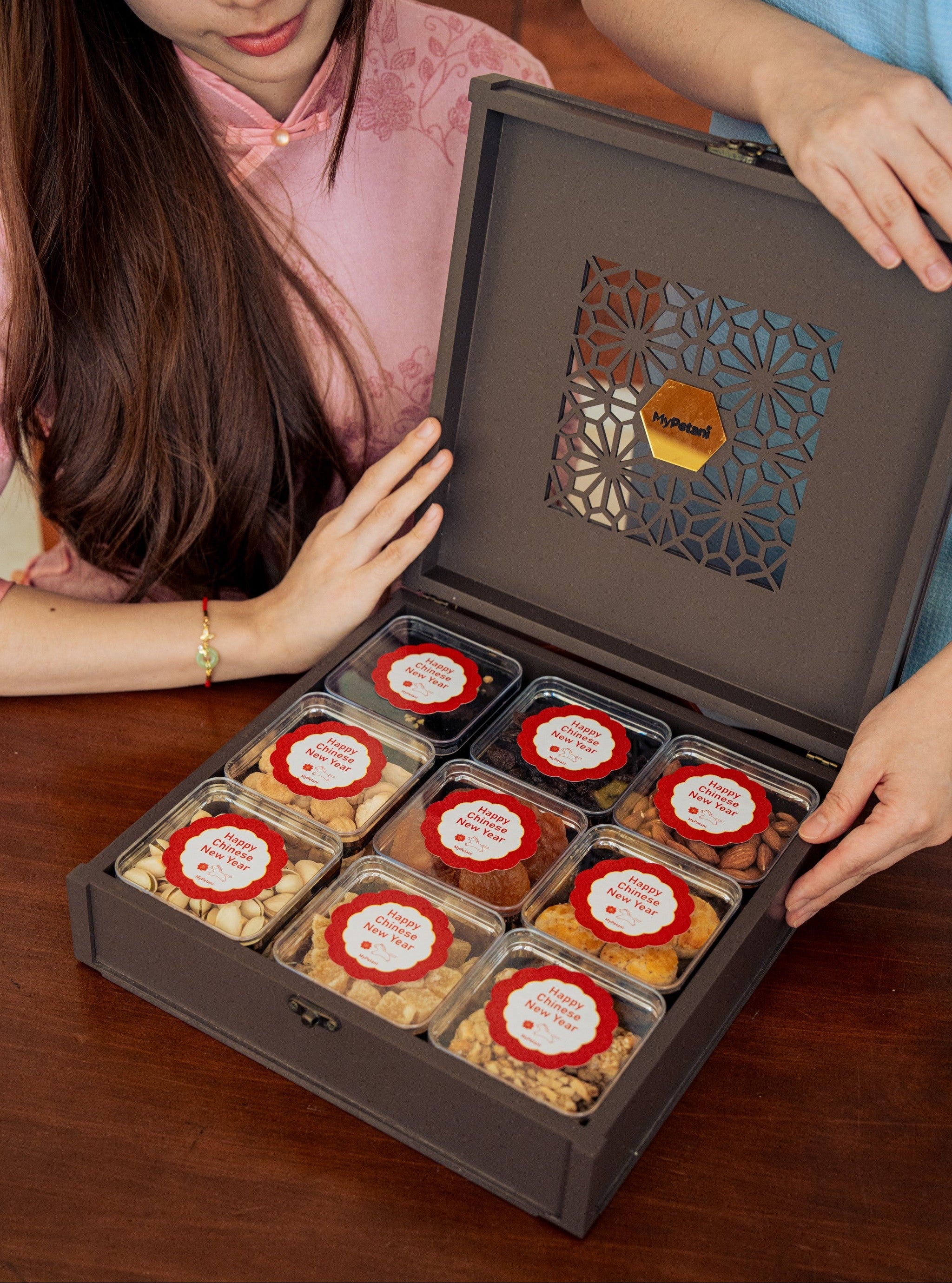 Person opening a box of assorted snacks with decorative labels.