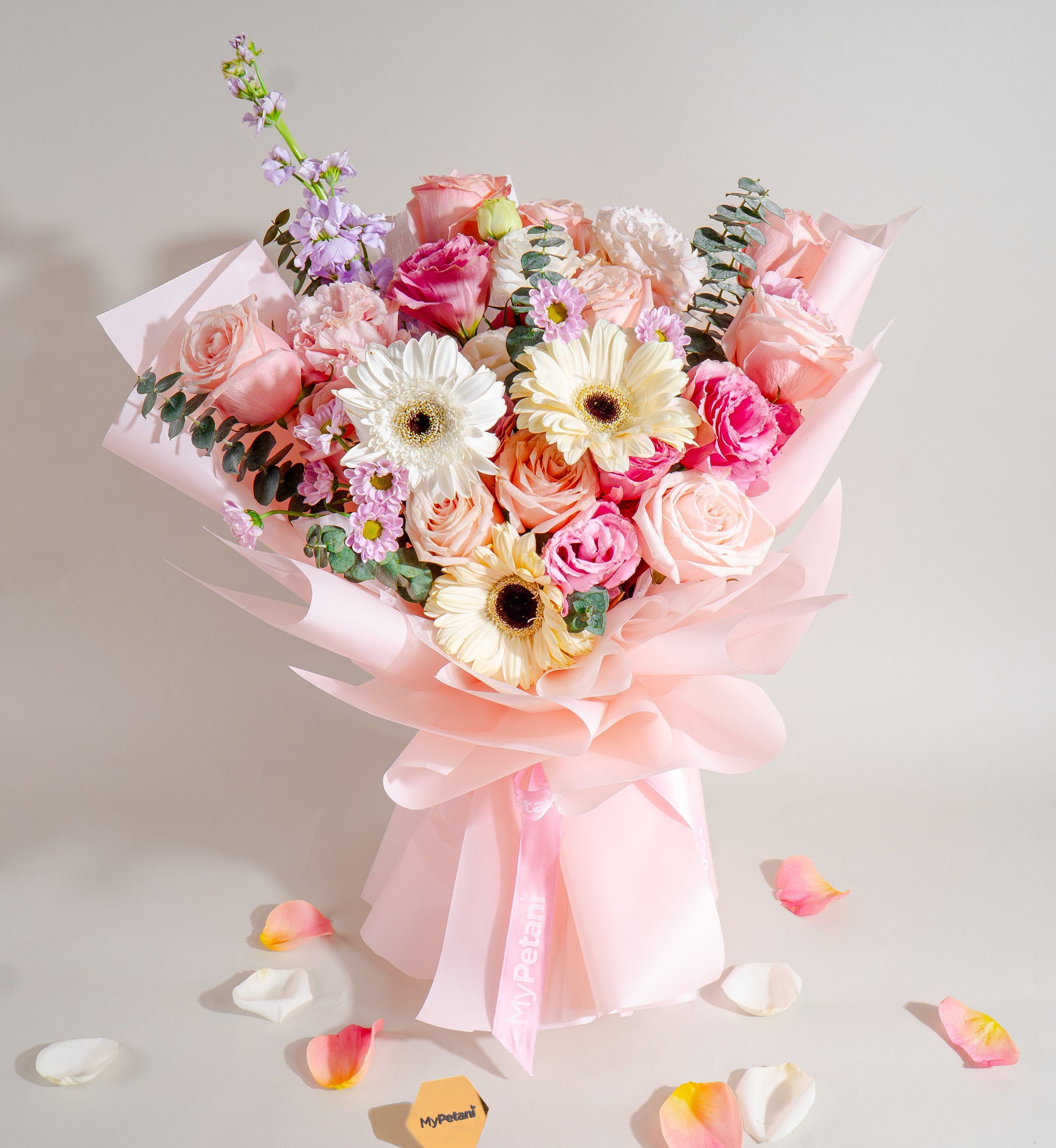 Bouquet of flowers with pink and white ribbons on a light gray background