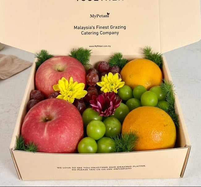 Fruit box with apples, oranges, and grapes on a light surface with a neutral background