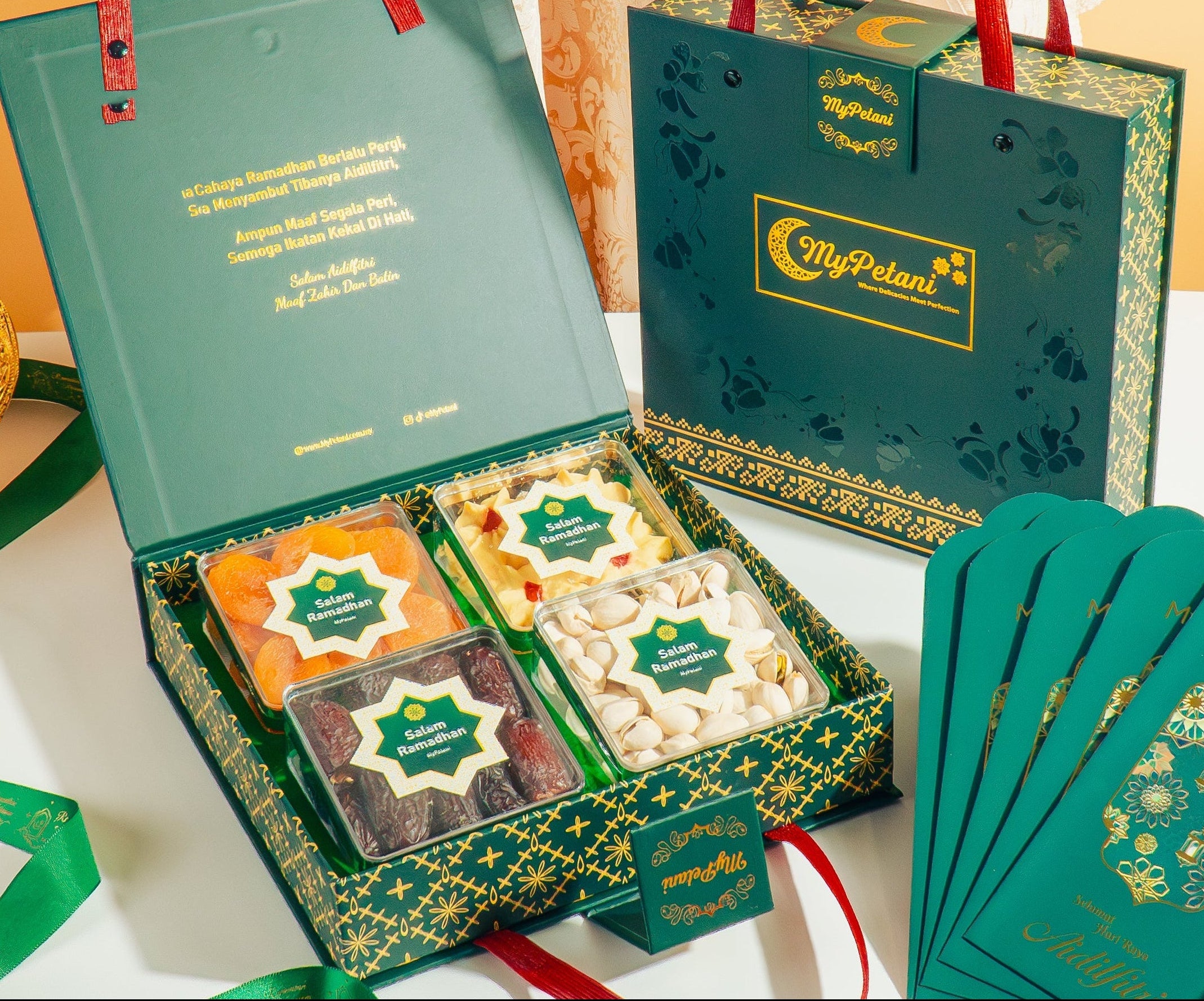 Gift set with green boxes, cookies, and cards on a decorative tablecloth.