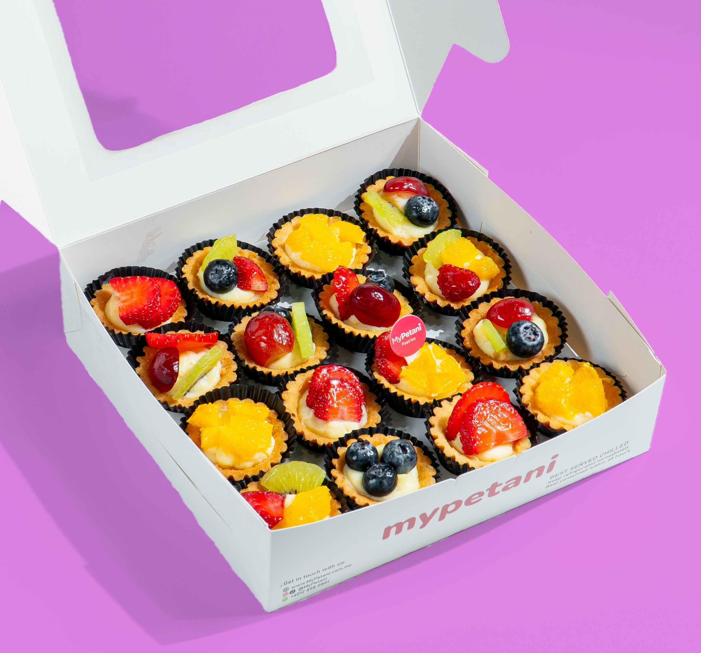 Box of small fruit tarts with 'mypetani' branding on a purple background