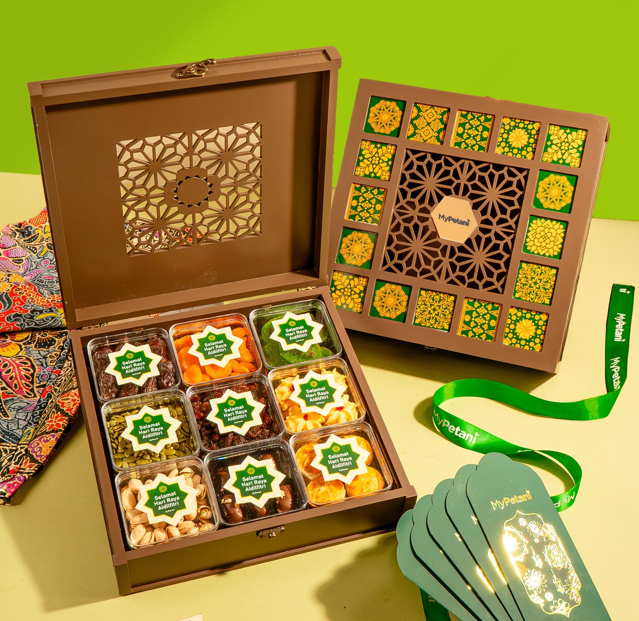 Open brown gift box with decorative compartments on a yellow surface, featuring a green background.