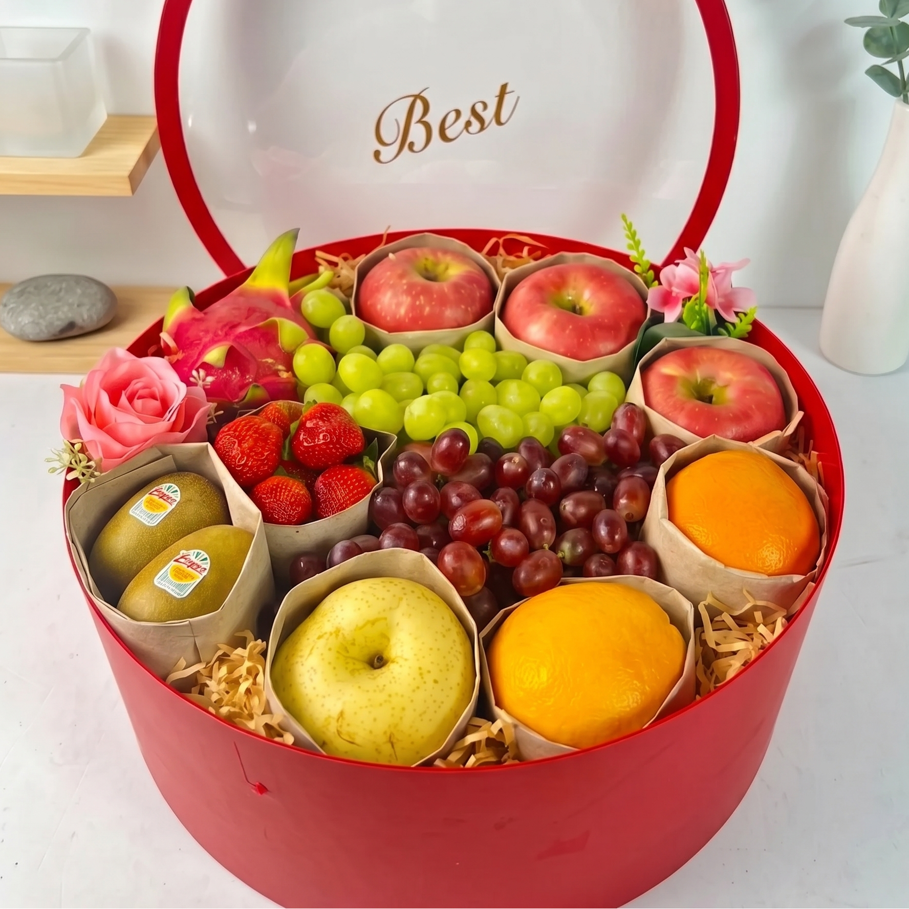 Fruit box with various fruits and flowers on a white surface